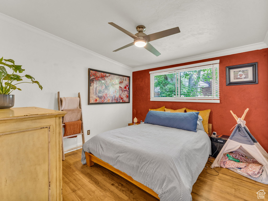 Bedroom with light wood-type flooring, crown molding, and a ceiling fan