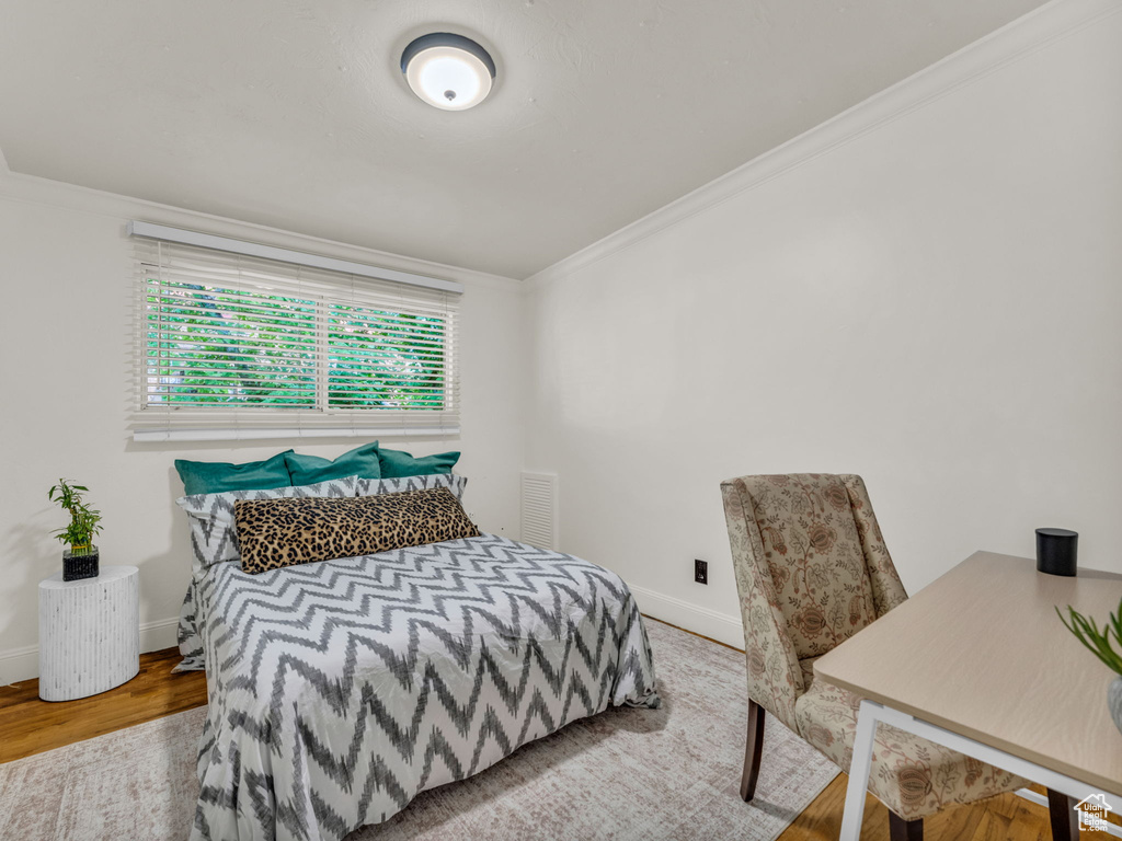 Bedroom with crown molding, wood finished floors, and baseboards