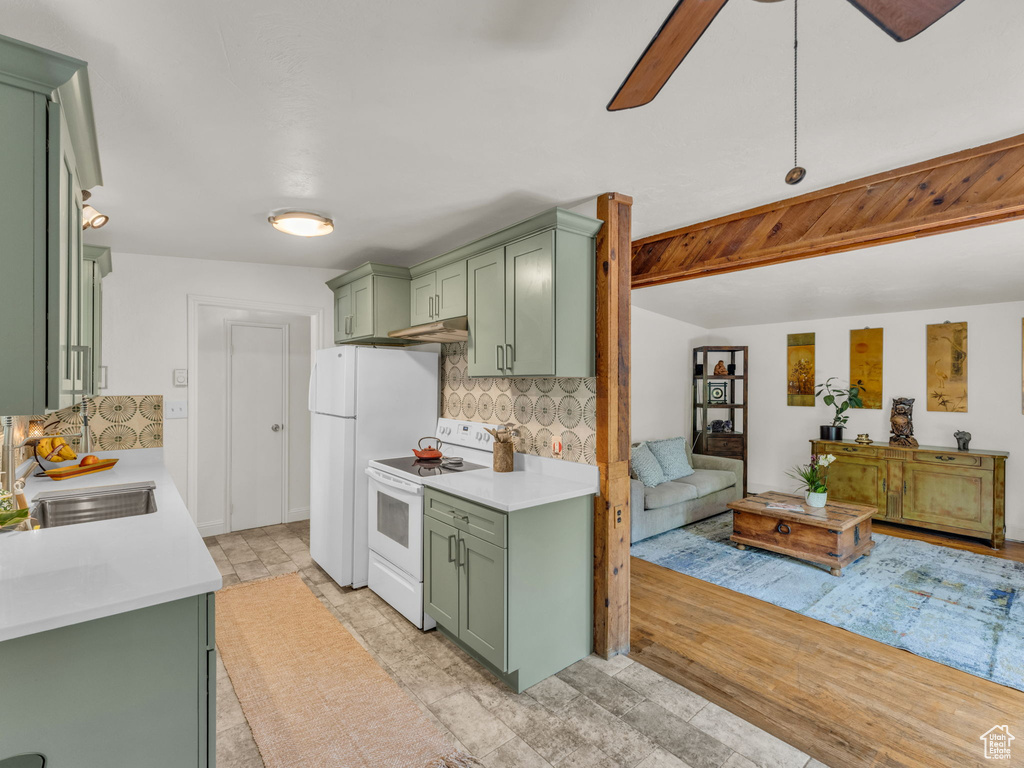 Kitchen with green cabinets, white appliances, backsplash, and light countertops