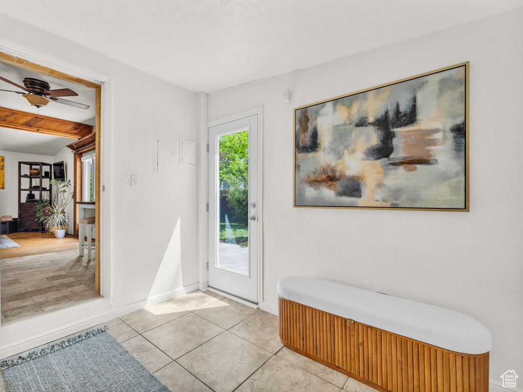 Foyer featuring a ceiling fan, light tile patterned floors, baseboards, and beamed ceiling