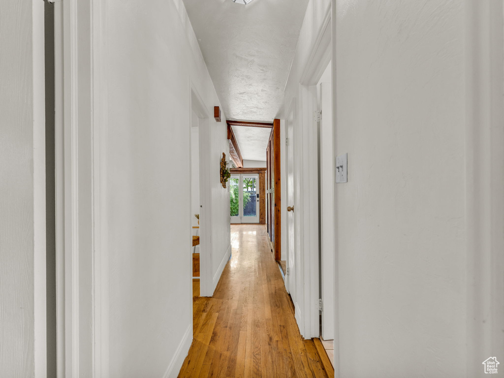 Corridor with light wood-style flooring and baseboards