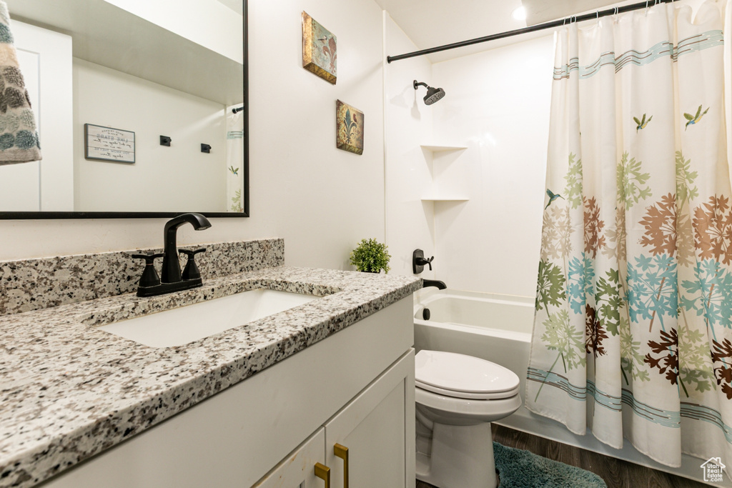 Full bath with vanity, toilet, shower / bath combination with curtain, and wood finished floors