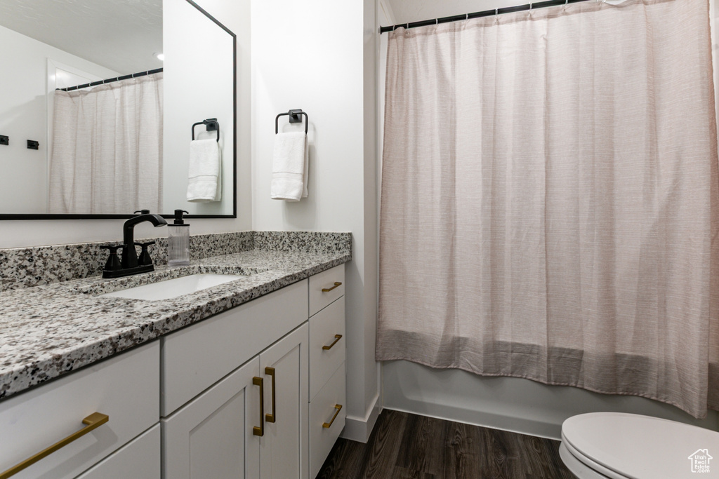 Bathroom featuring vanity, wood finished floors, toilet, and shower / bath combo