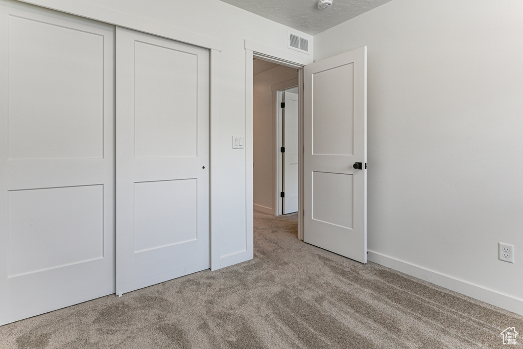 Unfurnished bedroom with carpet, a closet, and baseboards