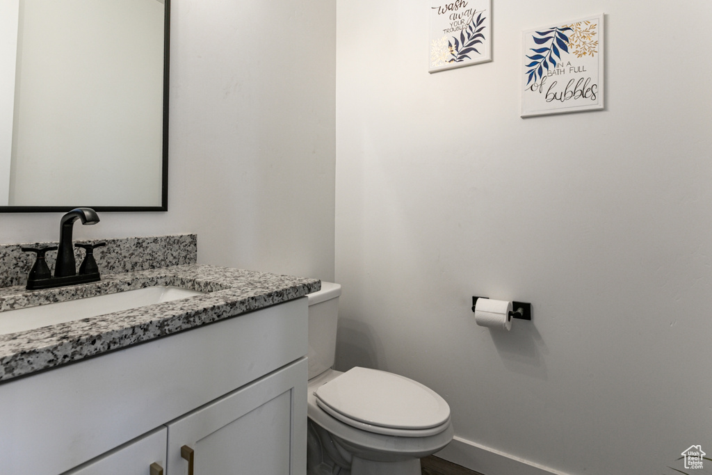 Bathroom featuring vanity, toilet, baseboards, and wood finished floors