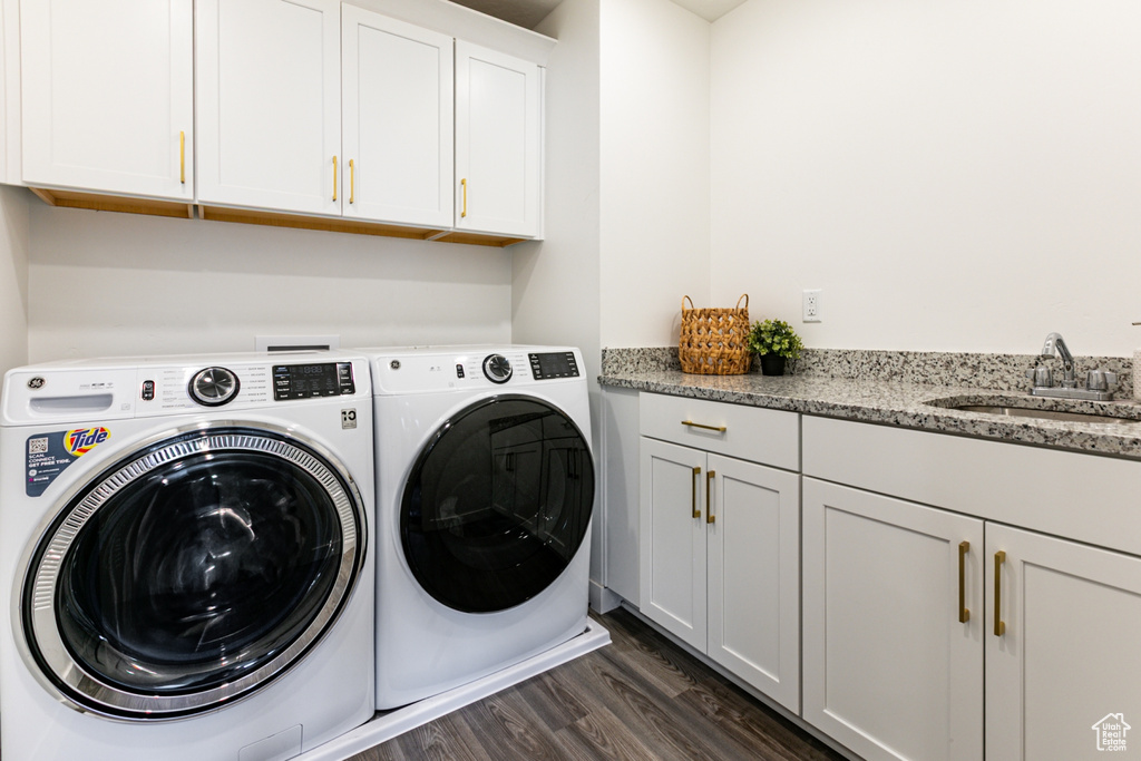 Laundry room featuring washer and clothes dryer, cabinet space, and dark wood-type flooring