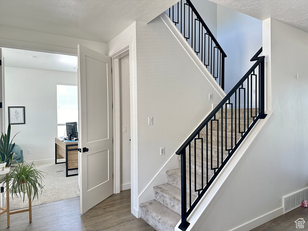 Stairs featuring wood finished floors, a textured ceiling, and baseboards