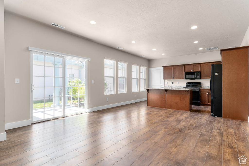 Kitchen featuring black appliances, recessed lighting, open floor plan, baseboards, and dark wood-style floors