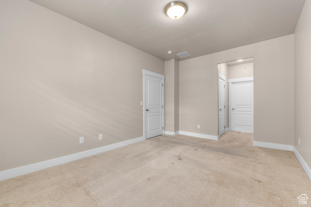 Unfurnished bedroom featuring light carpet, baseboards, and ensuite bathroom