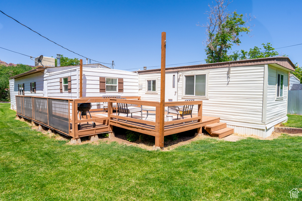 Back of house featuring a lawn and a deck