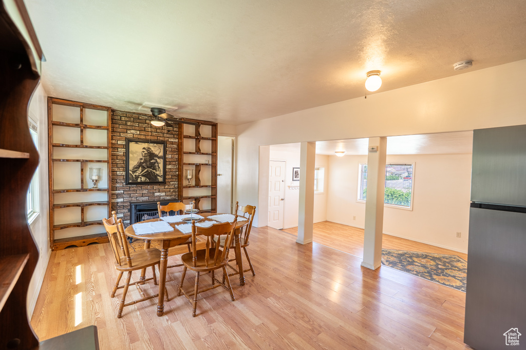Dining room with a ceiling fan, wood finished floors, a fireplace, and built in features