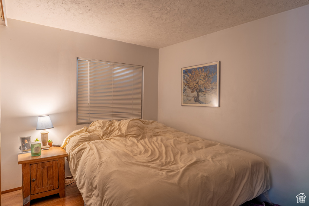 Bedroom with a textured ceiling and wood finished floors