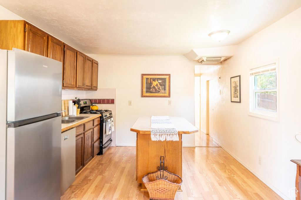 Kitchen with stainless steel appliances, light countertops, light wood-type flooring, and brown cabinetry