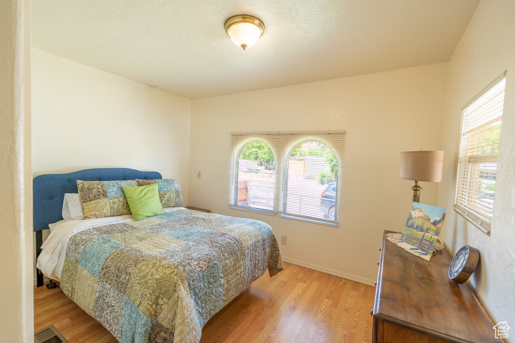 Bedroom with light wood-style flooring, multiple windows, and baseboards
