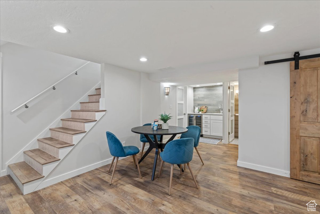 Dining space featuring baseboards, stairs, light wood-style floors, a barn door, and recessed lighting