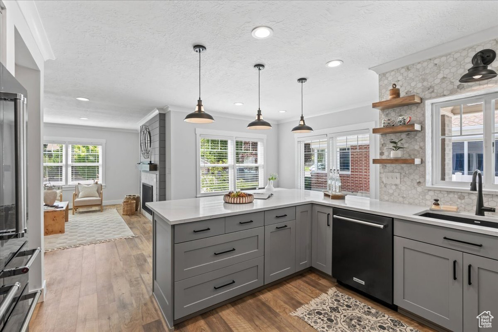 Kitchen featuring gray cabinets, dishwasher, a sink, a peninsula, and crown molding