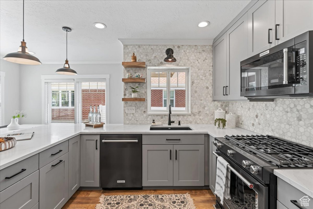 Kitchen featuring appliances with stainless steel finishes, a sink, gray cabinets, decorative backsplash, and ornamental molding