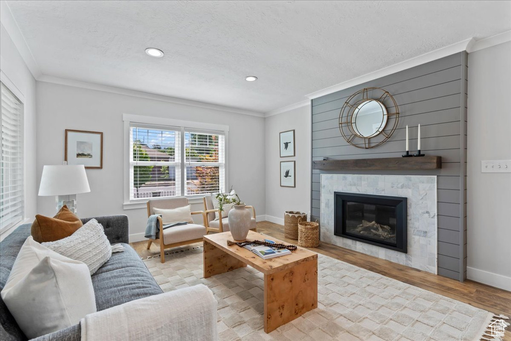 Living area featuring crown molding, a glass covered fireplace, baseboards, wood finished floors, and recessed lighting