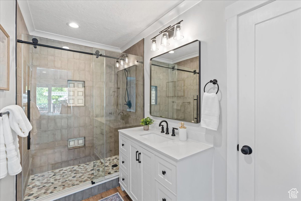 Full bath with vanity, a shower stall, ornamental molding, a textured ceiling, and recessed lighting