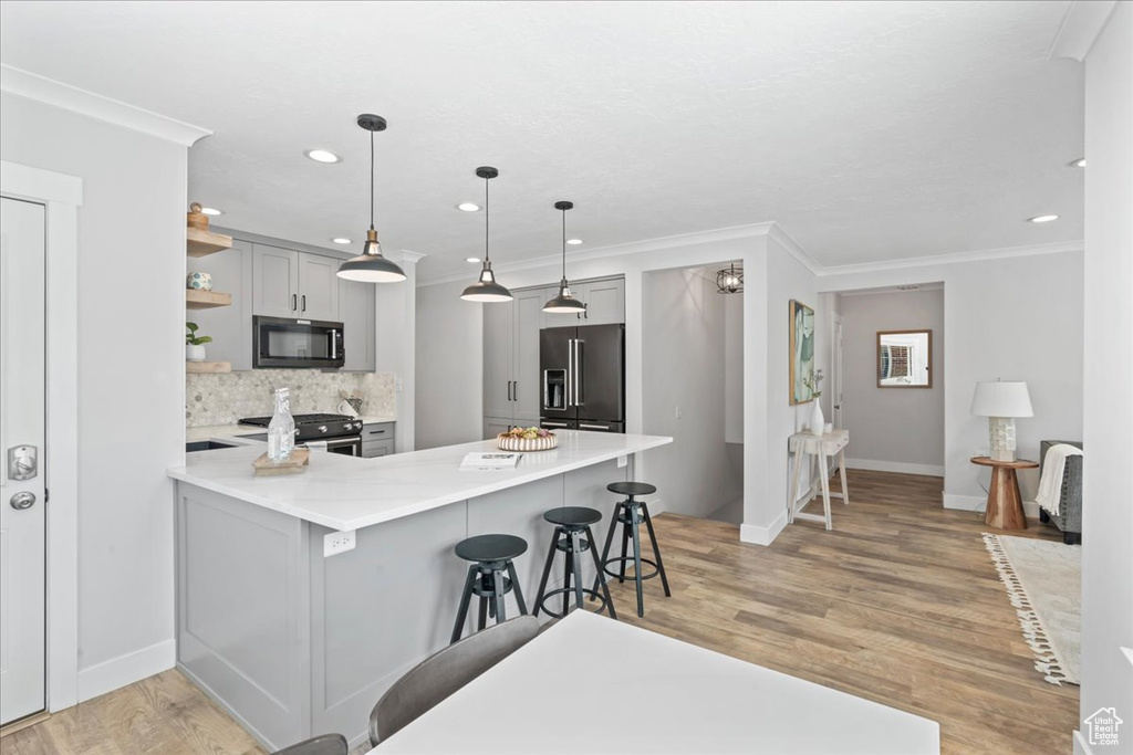 Kitchen featuring high quality fridge, gray cabinetry, black microwave, open shelves, and crown molding