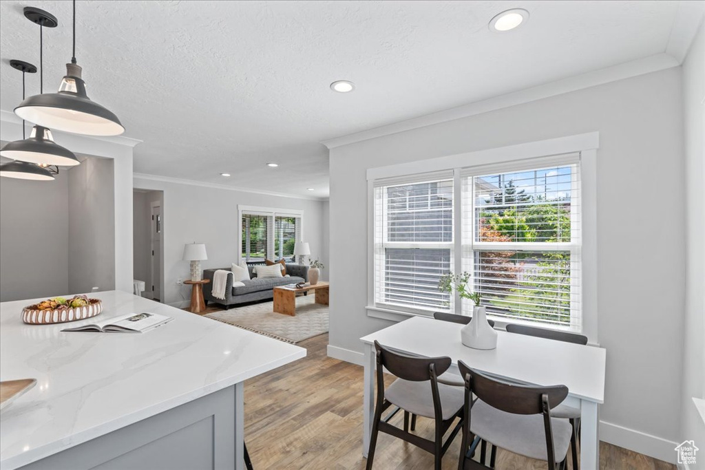 Kitchen featuring crown molding, recessed lighting, light stone countertops, light wood-style flooring, and baseboards