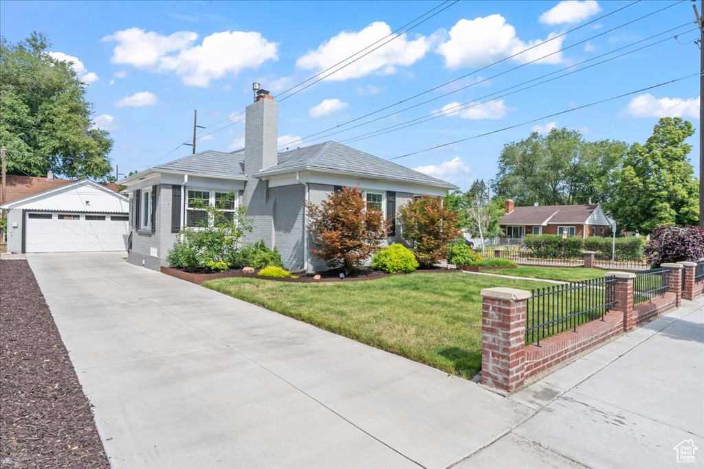 Ranch-style house featuring an outbuilding, a garage, a chimney, and brick siding