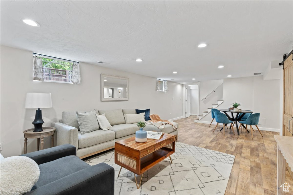Living area featuring a barn door, stairs, recessed lighting, light wood-type flooring, and baseboards