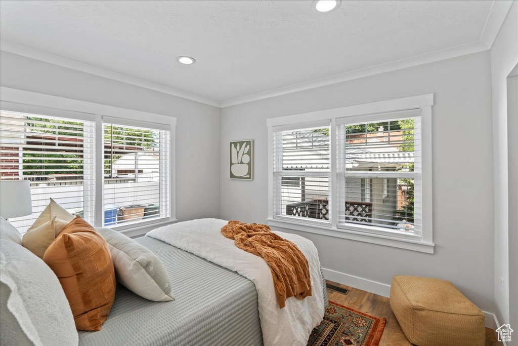 Bedroom featuring crown molding, wood finished floors, baseboards, and recessed lighting