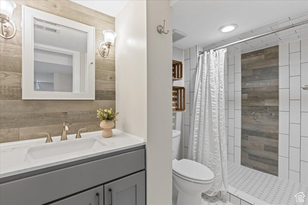 Full bath with toilet, vanity, and a stall shower