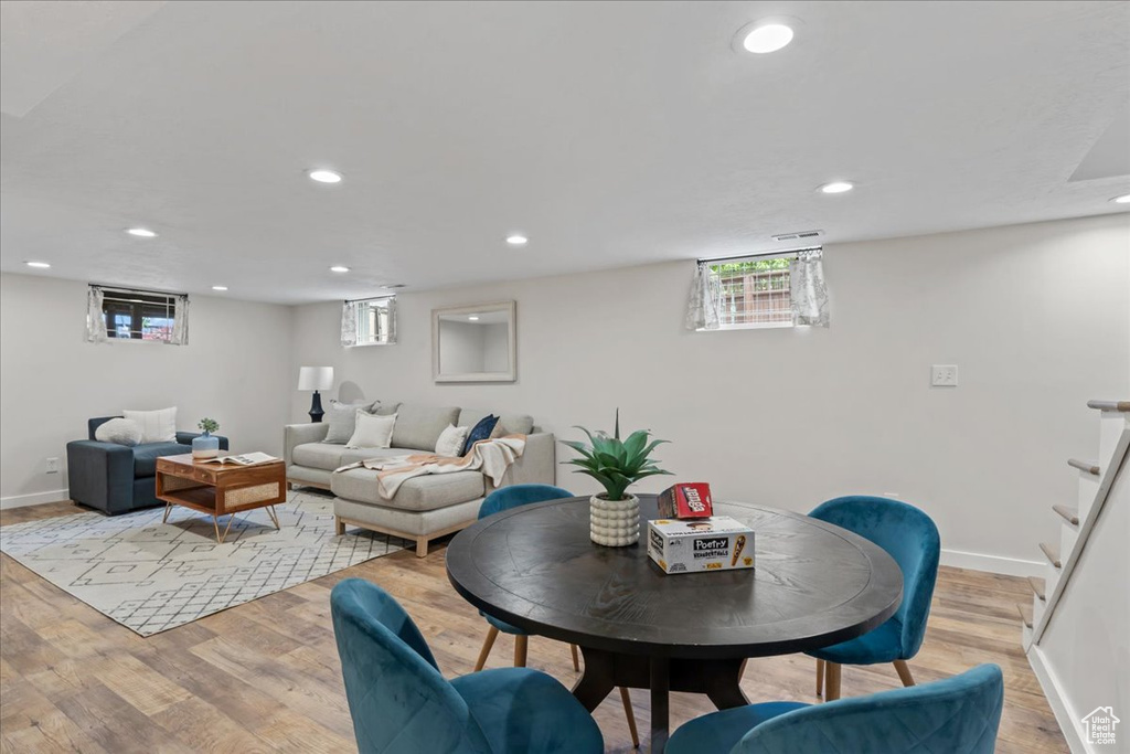 Living area featuring light wood finished floors, baseboards, stairway, recessed lighting, and plenty of natural light