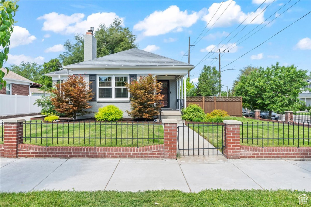 View of front of house featuring a chimney and a gate
