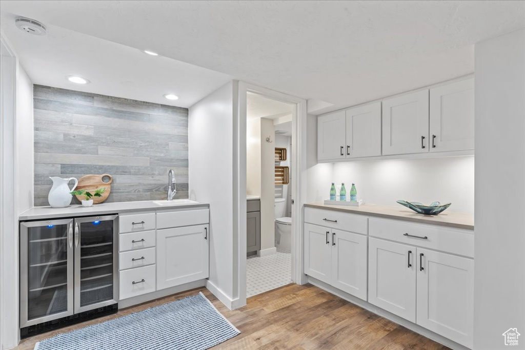 Indoor wet bar with wine cooler, light wood-style flooring, recessed lighting, and baseboards