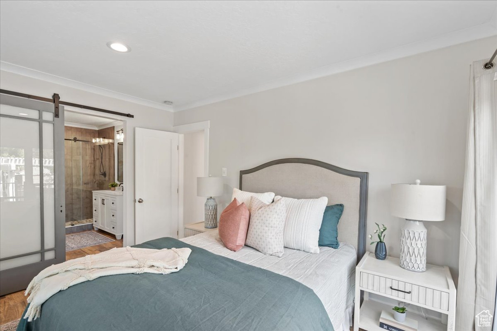 Bedroom featuring ornamental molding, wood finished floors, and ensuite bathroom