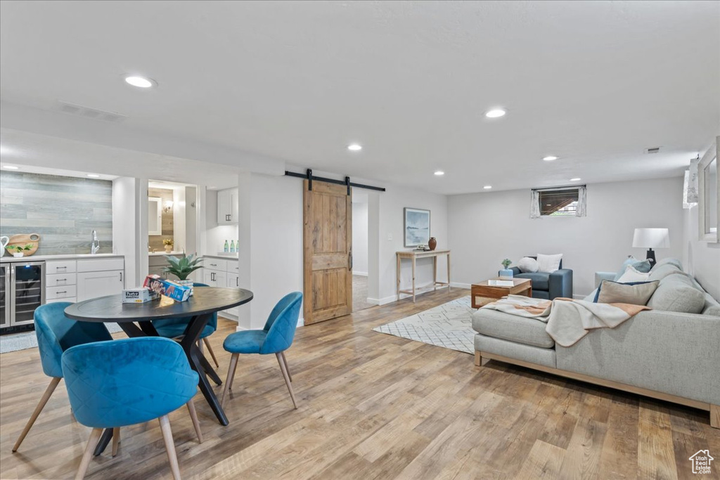 Living room featuring beverage cooler, bar area, a barn door, recessed lighting, and light wood finished floors