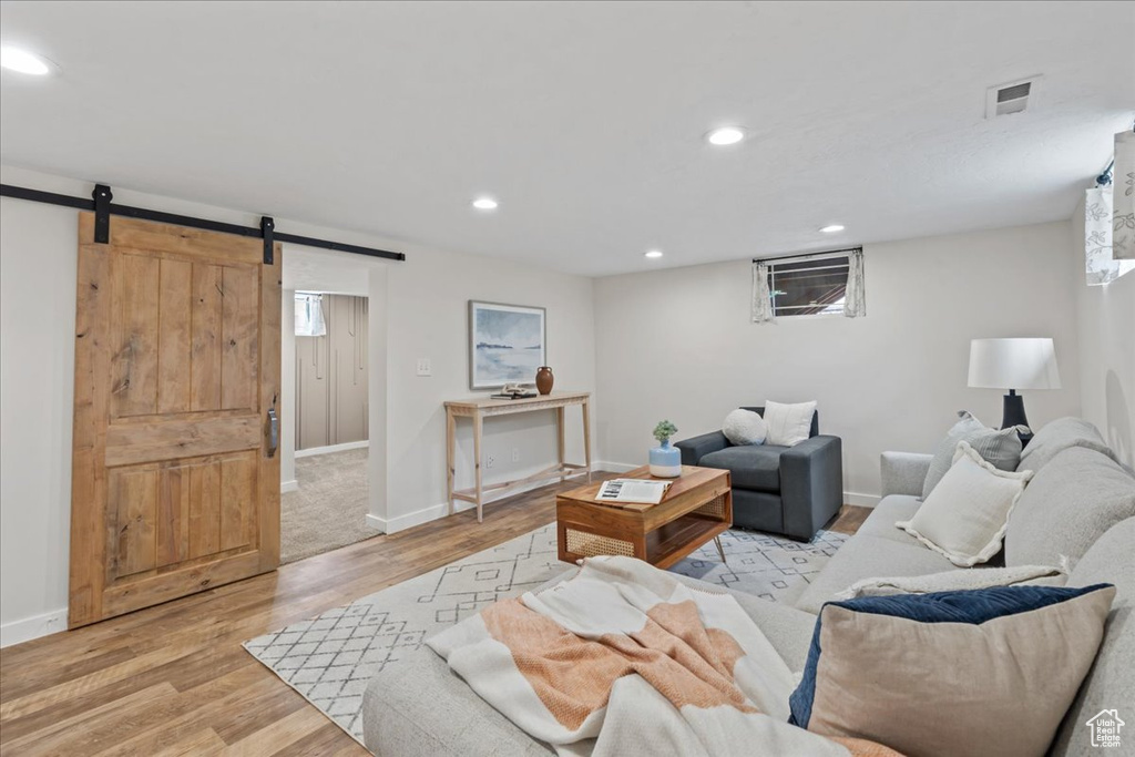 Living room with a barn door, light wood-style floors, baseboards, and recessed lighting