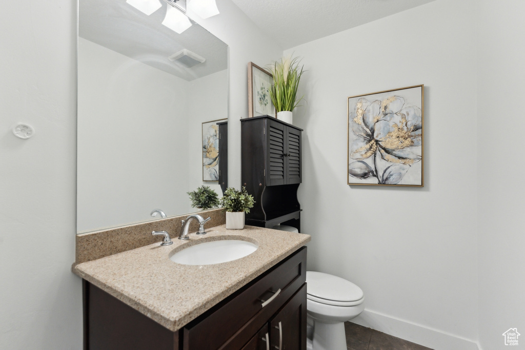 Half bath featuring vanity, tile patterned floors, toilet, and a skylight