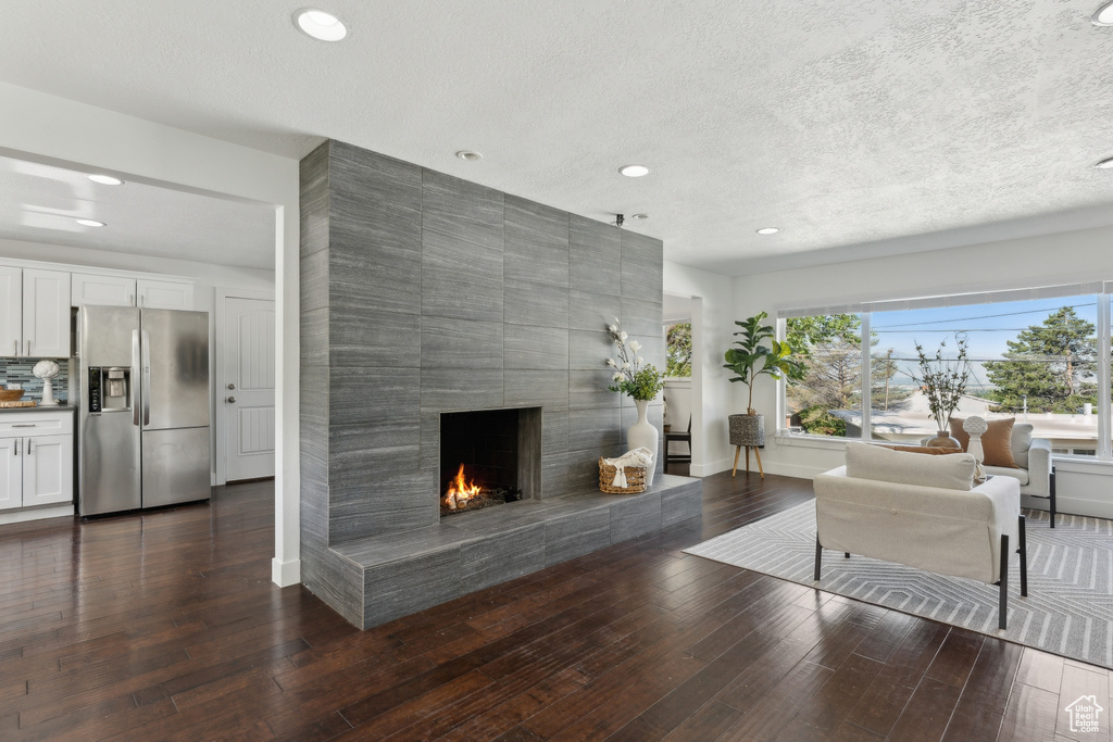 Living room featuring a fireplace, recessed lighting, dark wood-style flooring, a textured ceiling, and baseboards