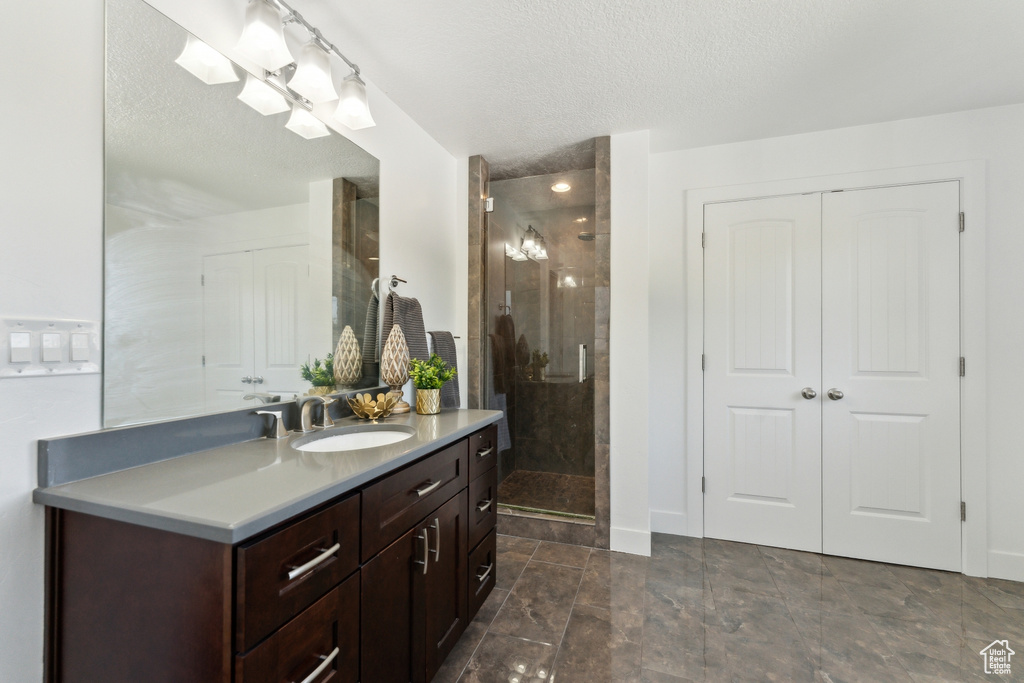 Bathroom with vanity, a shower stall, and a textured ceiling