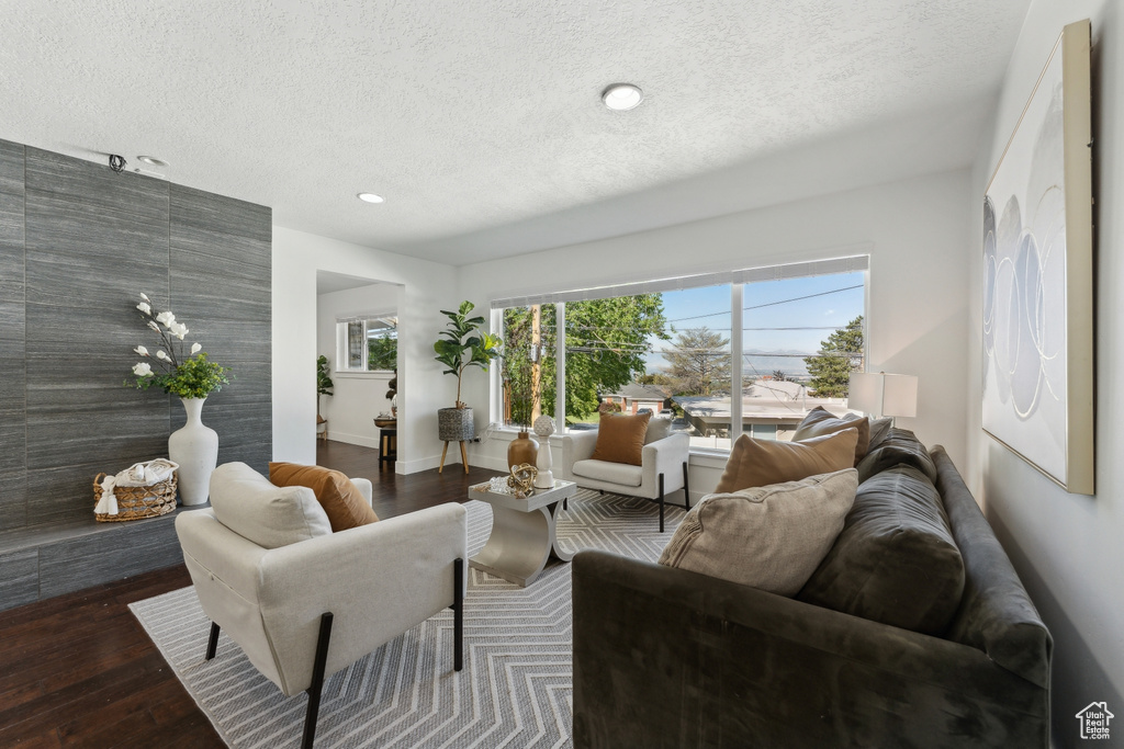Living room with a textured ceiling, wood finished floors, recessed lighting, and baseboards