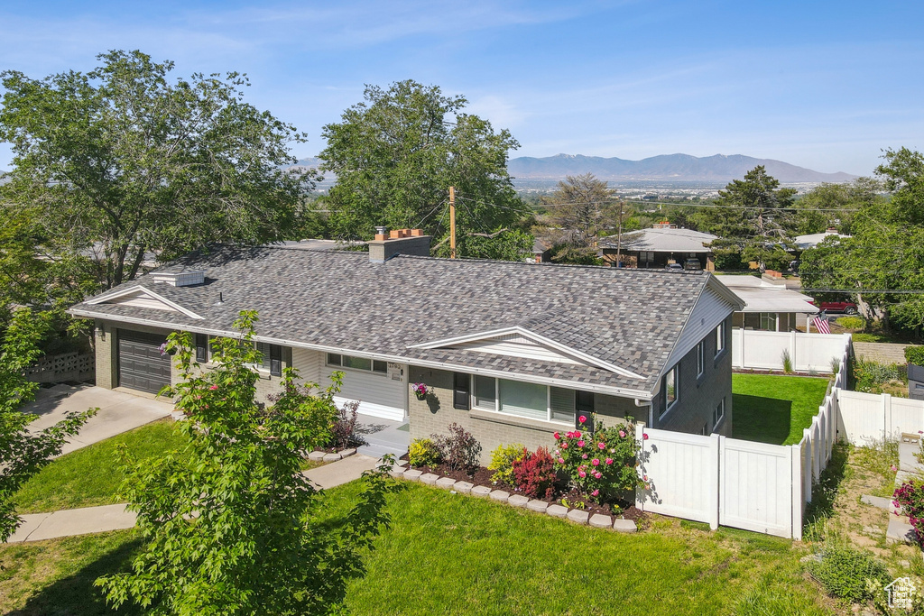 View of front of home featuring a garage, driveway, a chimney, a mountain view, and brick siding