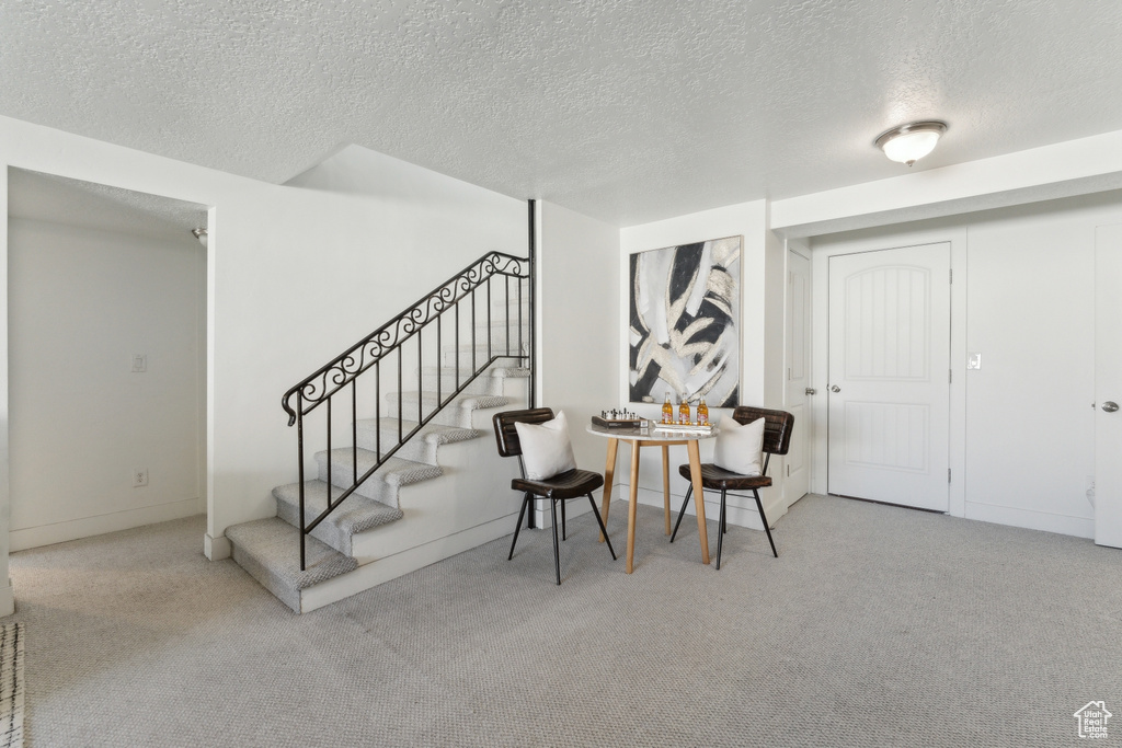 Entryway with a textured ceiling, carpet floors, and stairway