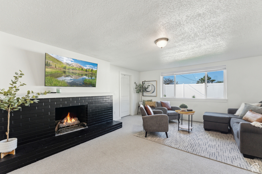 Living room with carpet, a brick fireplace, and a textured ceiling