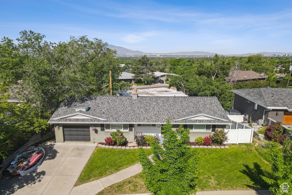 View of front of home featuring driveway, a mountain view, a garage, and a shingled roof