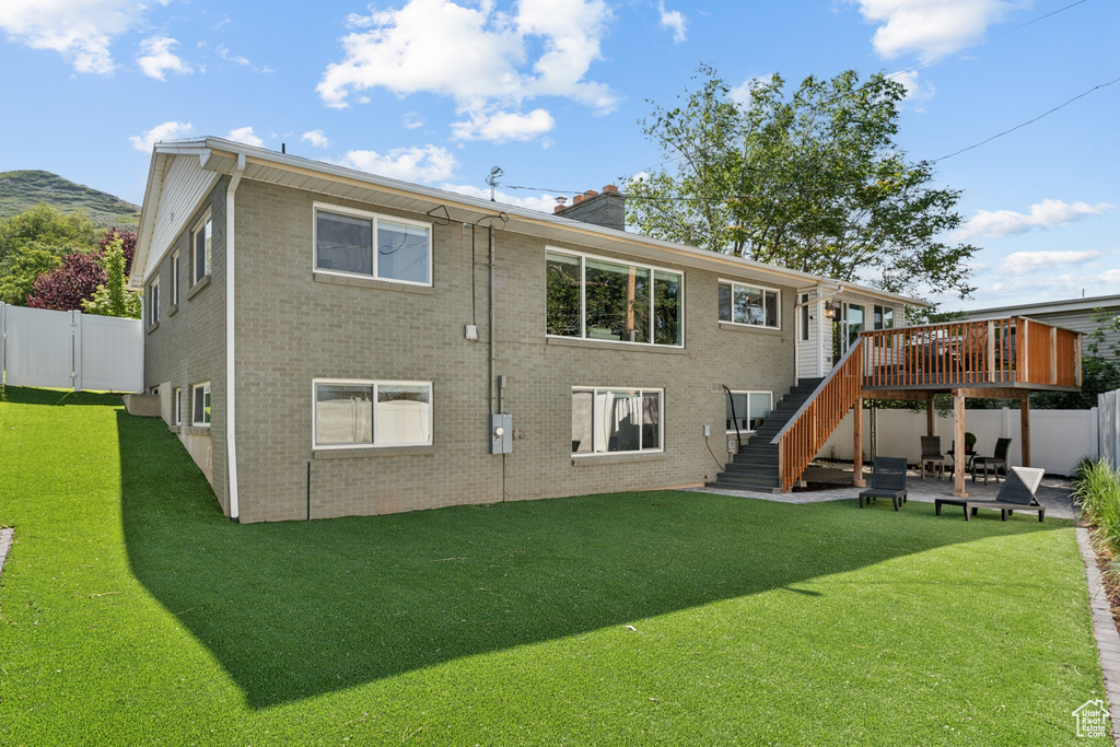 Back of house with stairway, a wooden deck, a patio area, a chimney, and brick siding
