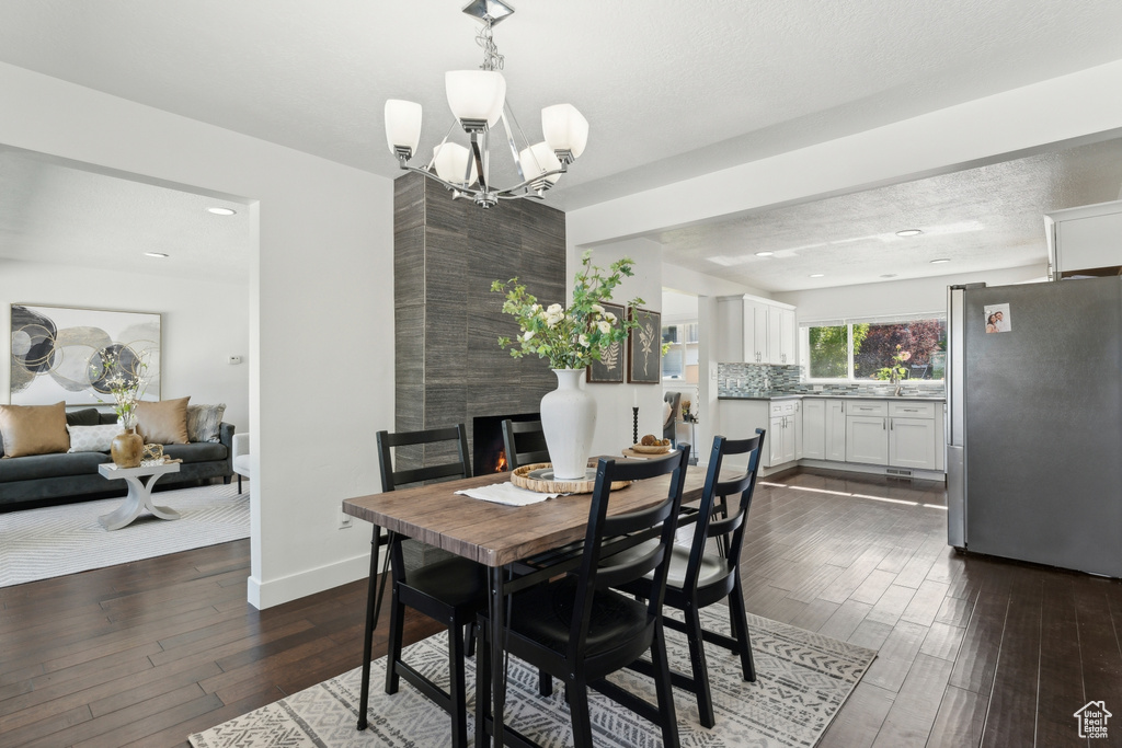 Dining space featuring dark wood finished floors, a fireplace, a chandelier, and baseboards