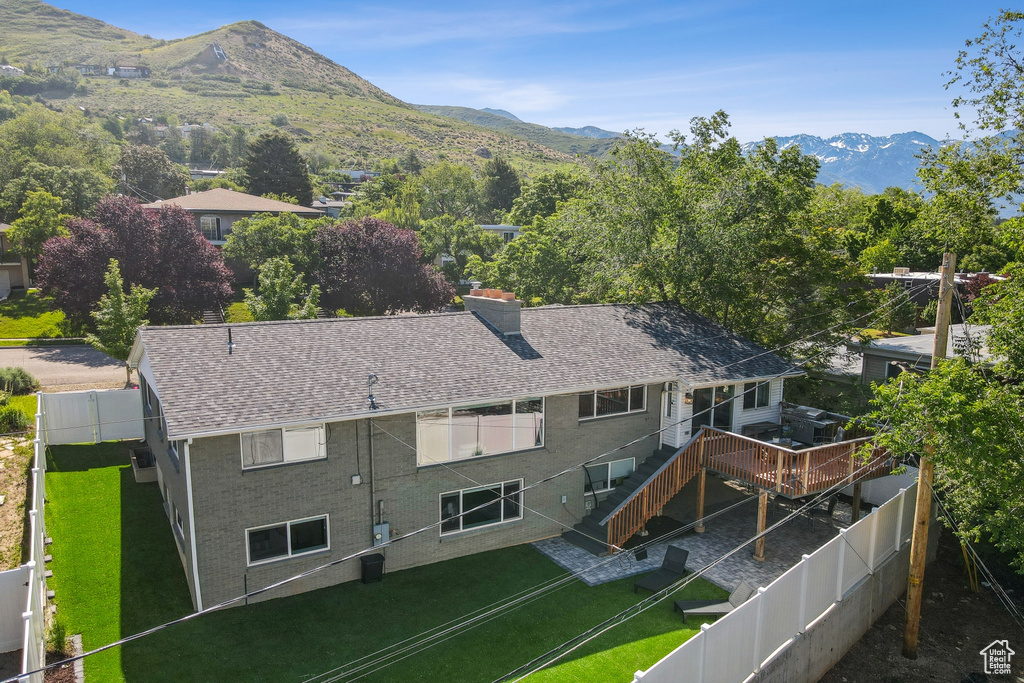 Rear view of property featuring a mountain view, roof with shingles, and a chimney