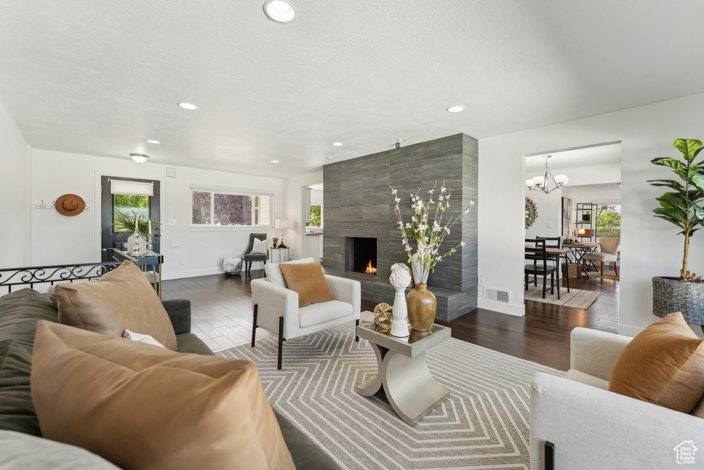 Living area featuring wood finished floors, recessed lighting, a large fireplace, baseboards, and a chandelier