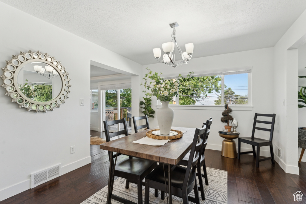 Dining space with a chandelier, baseboards, dark wood-type flooring, and a textured ceiling