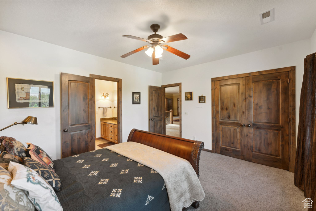 Carpeted bedroom featuring ceiling fan and ensuite bathroom