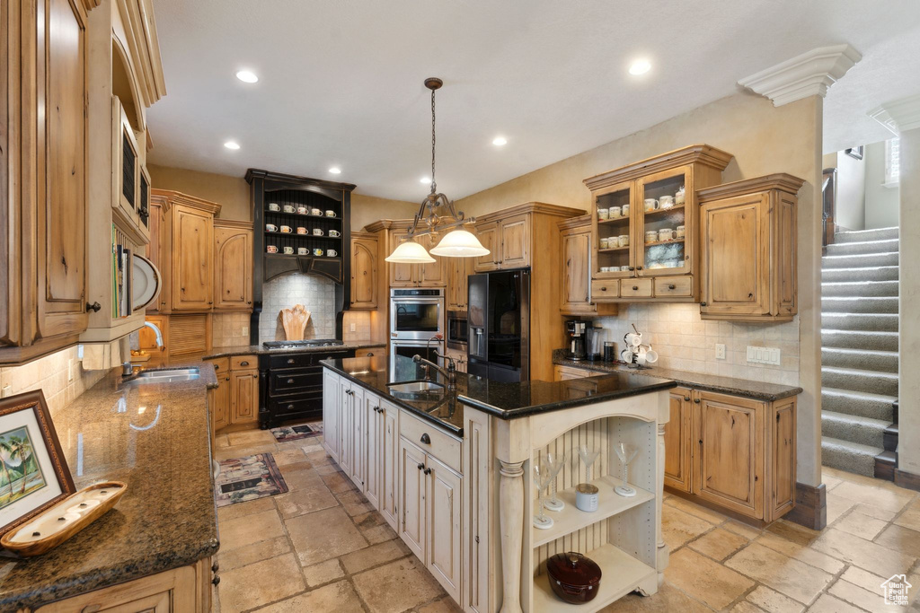 Kitchen featuring appliances with stainless steel finishes, a sink, open shelves, a center island with sink, and tasteful backsplash